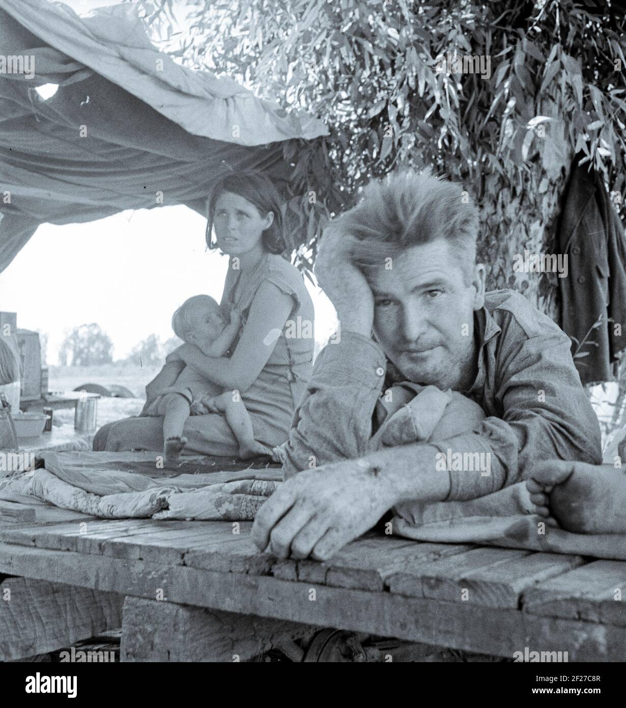 Photograph shows Zella (McCann) Power, wife of Jess Power with their baby Jesse Power. Drought refugees from Oklahoma camping by the roadside. They hope to work in the cotton fields. The official at the border (California-Arizona) inspection service said that on this day, August 17, 1936, twenty-three car loads and truck loads of migrant families out of the drought counties of Oklahoma and Arkansas had passed through that station entering California up to 3 o'clock in the afternoon . August 1936. Photograph by Dorothea Lange Stock Photo