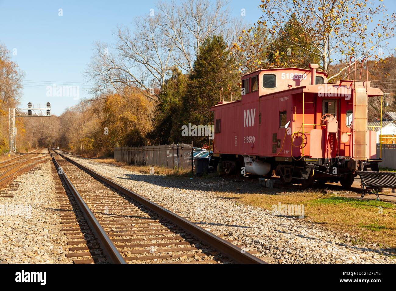 Clifton, VA, USA 11/14/2020: View of the train tracks, ballast, track sleepers and an abandoned red caboose passenger train cabin in front of historic Stock Photo