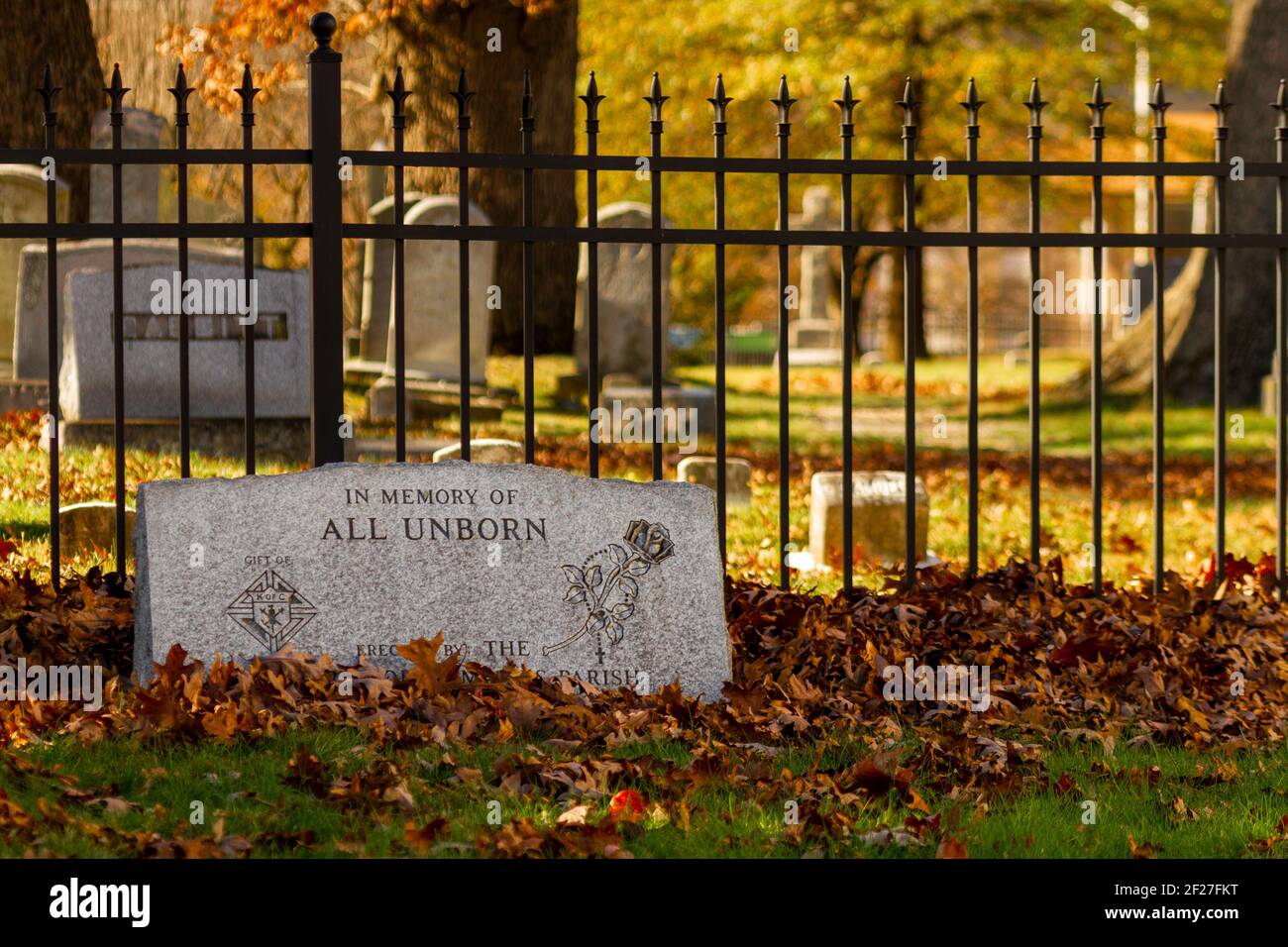 Rockville, MD, USA, 11/16/2020: A tombstone in the  grave yard by historic Saint Mary's Church with fallen leaves covering it. It is erected for the m Stock Photo