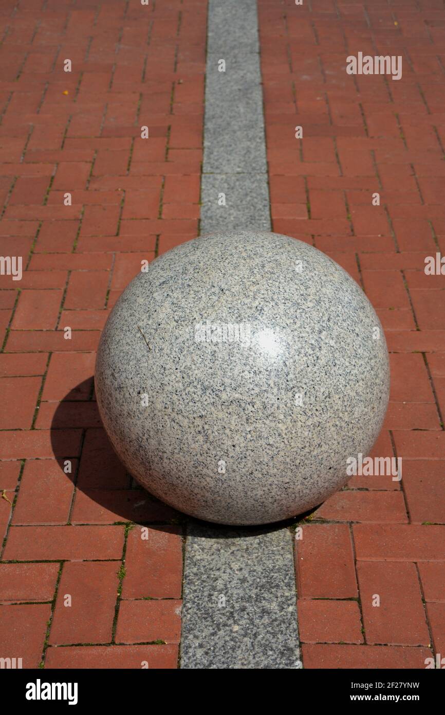 decorative granite ball sphere on sidewalk in street Stock Photo