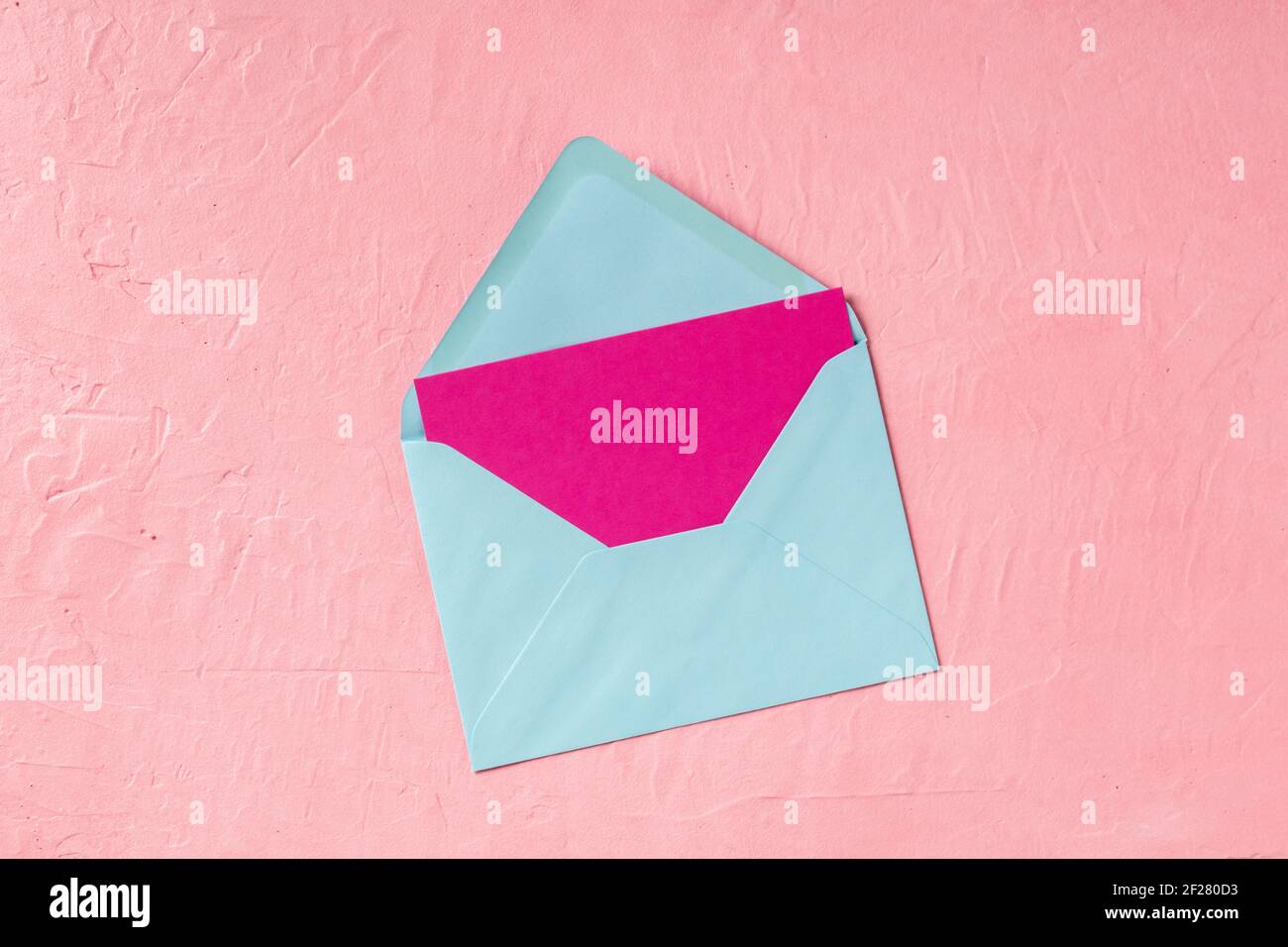Pink greeting card or invitation mockup in a blue envelope, shot from