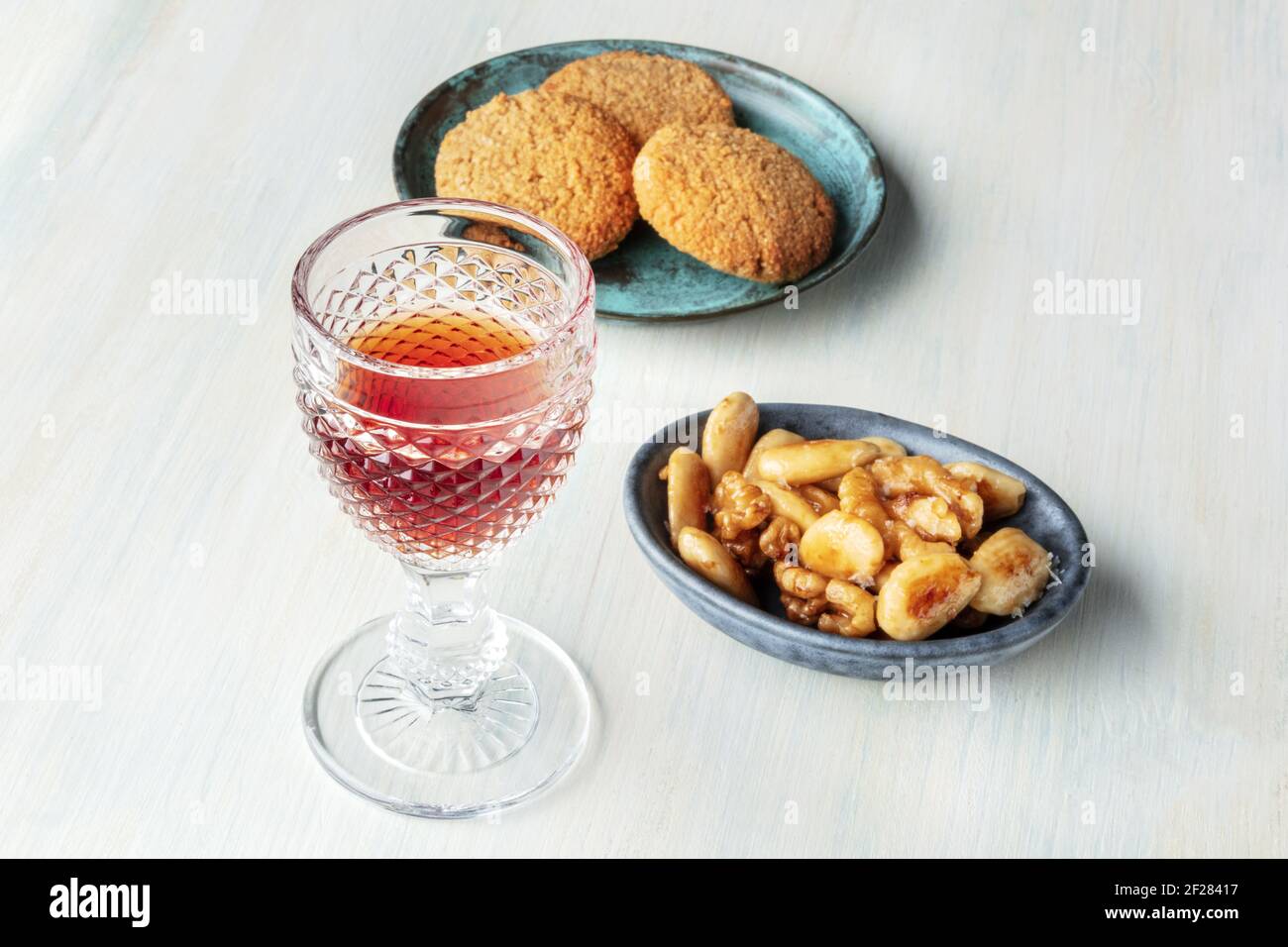 A photo of a glass of sweet wine with cookies and nuts Stock Photo