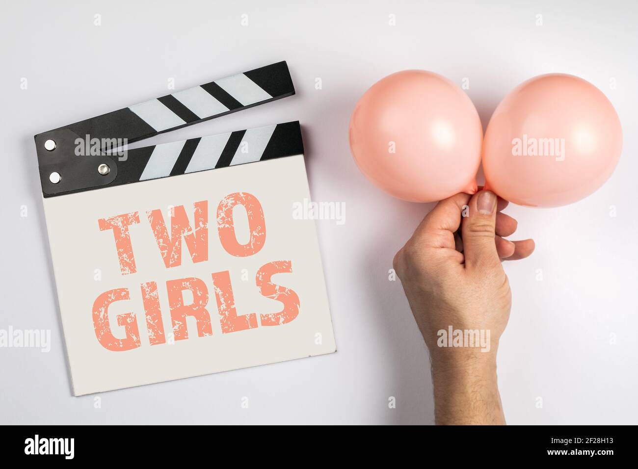TWO GIRLS. Birthday and sonographic examination concept. Movie clapper and a pink balloon on a white background. Stock Photo