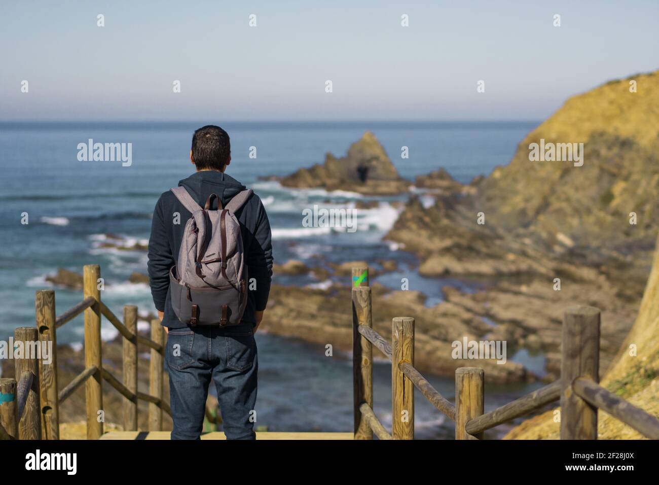 Man with a backpack seeing Praia dos Machados beach in Costa Vicentina, Portugal Stock Photo