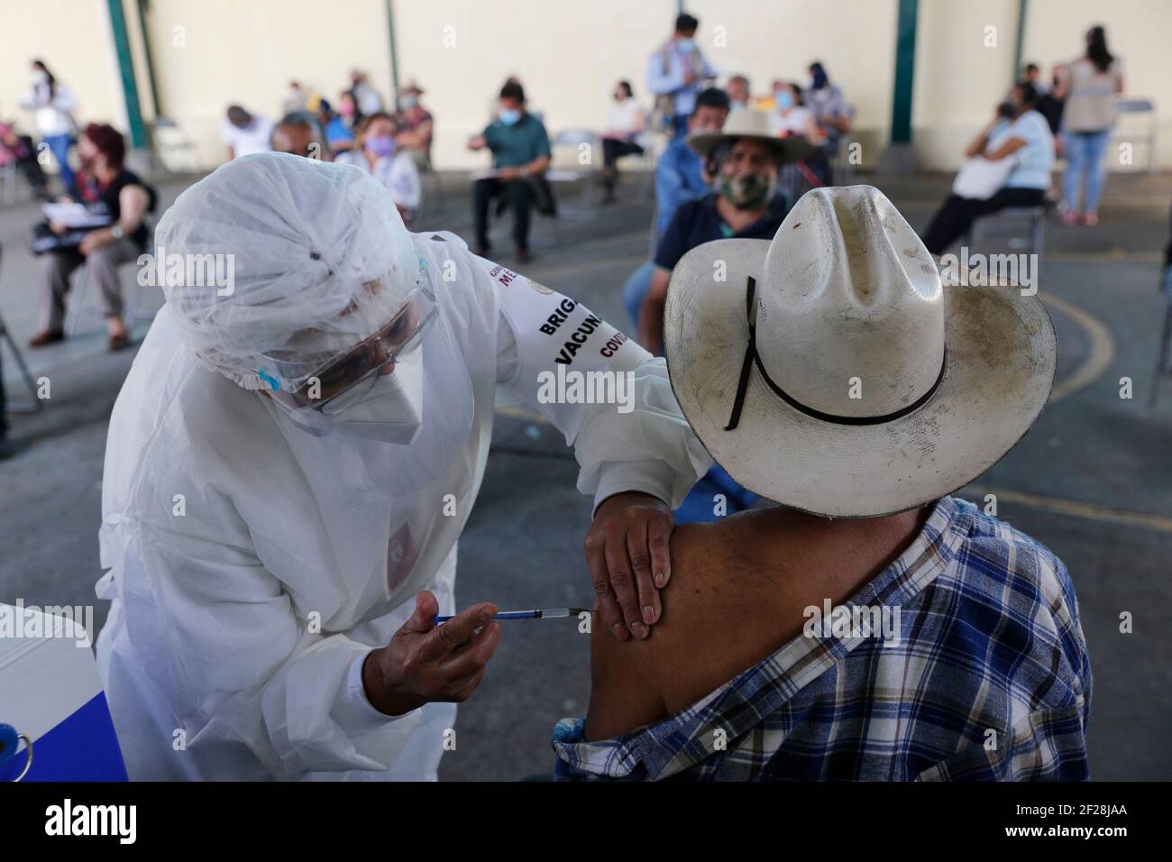Uruapan, Michoacan, Mexico. 10th Mar, 2021. A person receives a dose of Pfizer-BioNTech Covid-19 vaccine before inject to an elderly, during mass vaccine inside of Hermanos Lopez Rayon sports center, a designated priority vaccination center for elderly over 60 years in the Uruapan town. On March 10, 2021 in Michoacan, Mexico. Credit: Carlos Guzman/eyepix/ZUMA Wire/Alamy Live News Stock Photo