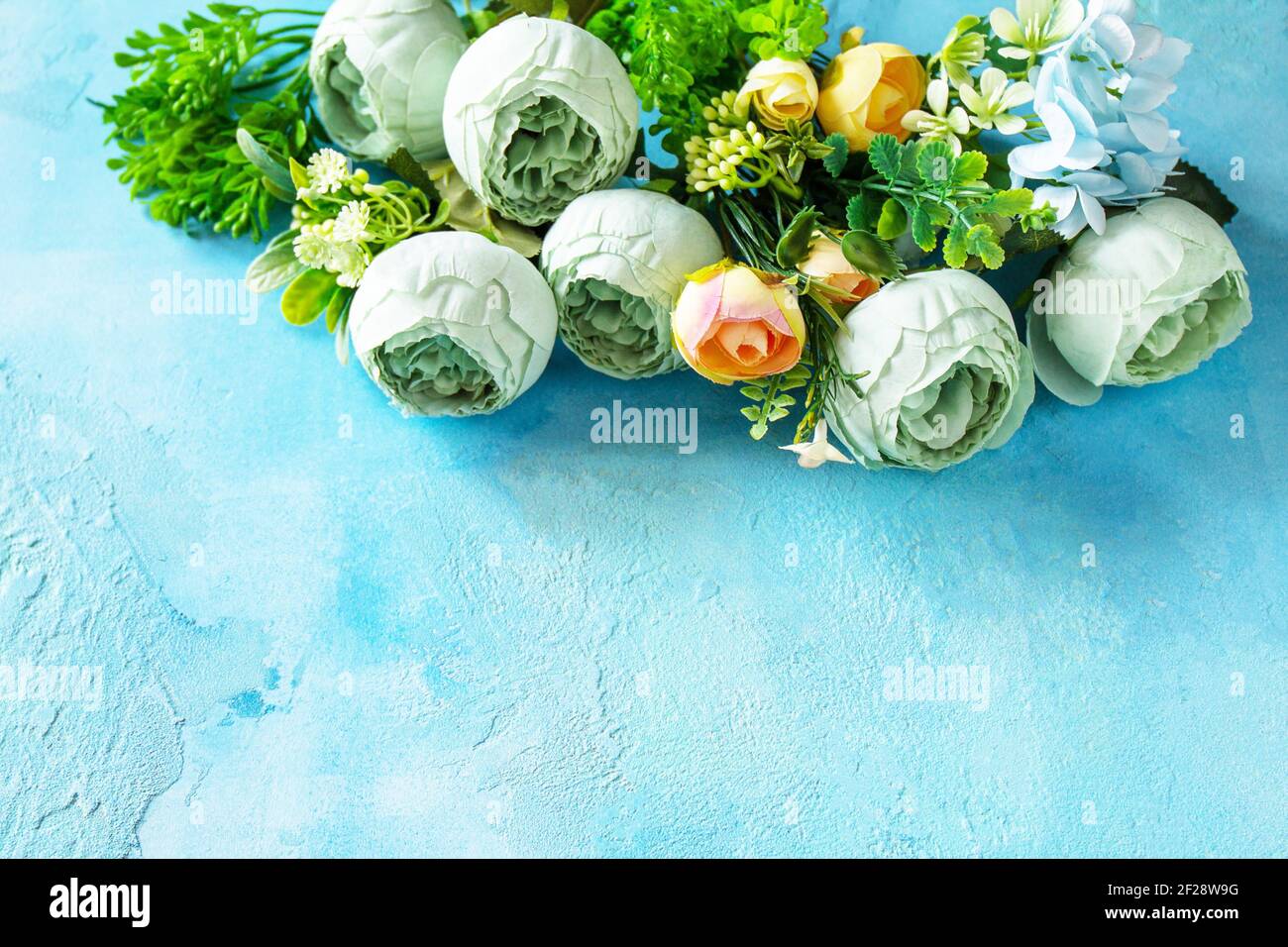 Happy Easter background. Spring flowers on a concrete blue background. Copy space. Stock Photo