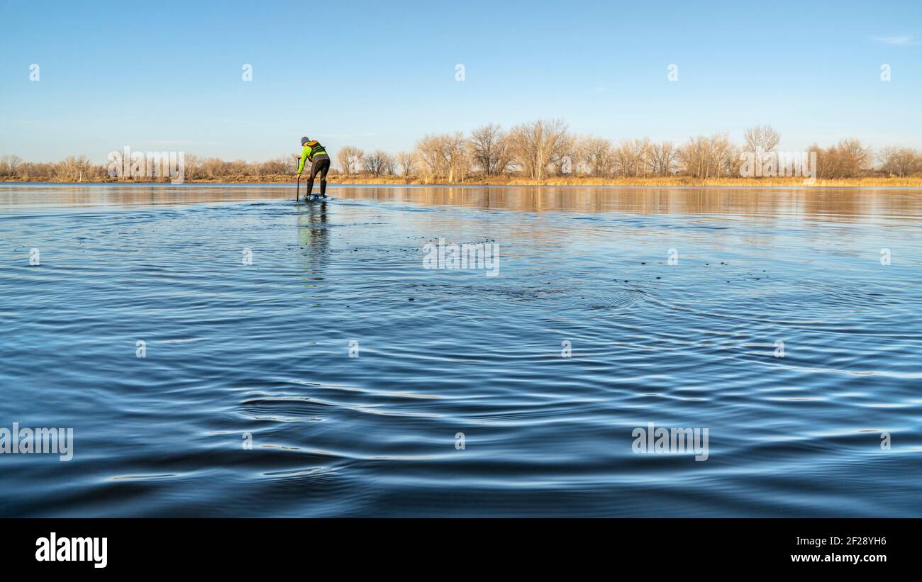 senior male stand up paddler is starting his paddling season on a  lake in Colorado Stock Photo