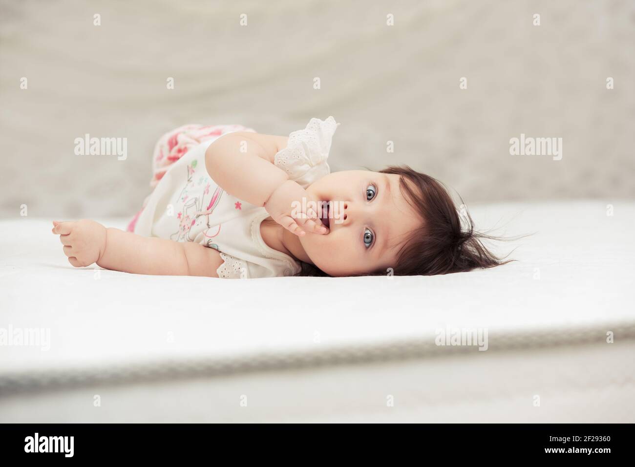 Happy six months old baby girl lying on blanket at home Stock Photo Alamy