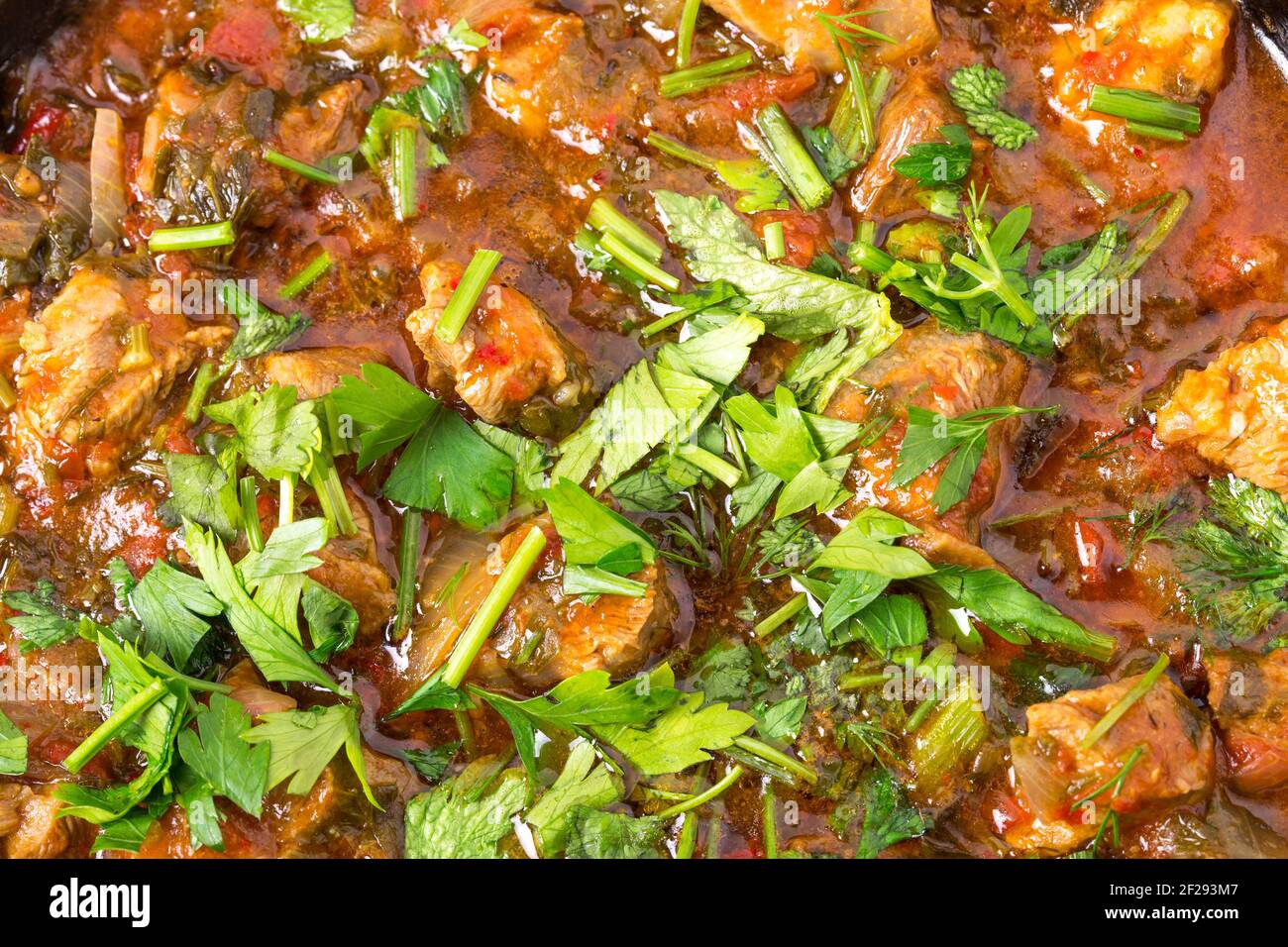 Delicious stewed lamb fillet with tomatoes and minced parsley. Macro. Photo can be used as a whole background. Stock Photo