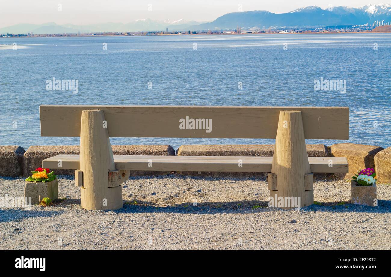 Wooden bench in front of the sea. Beautiful view of the mountains in the background. Stock Photo
