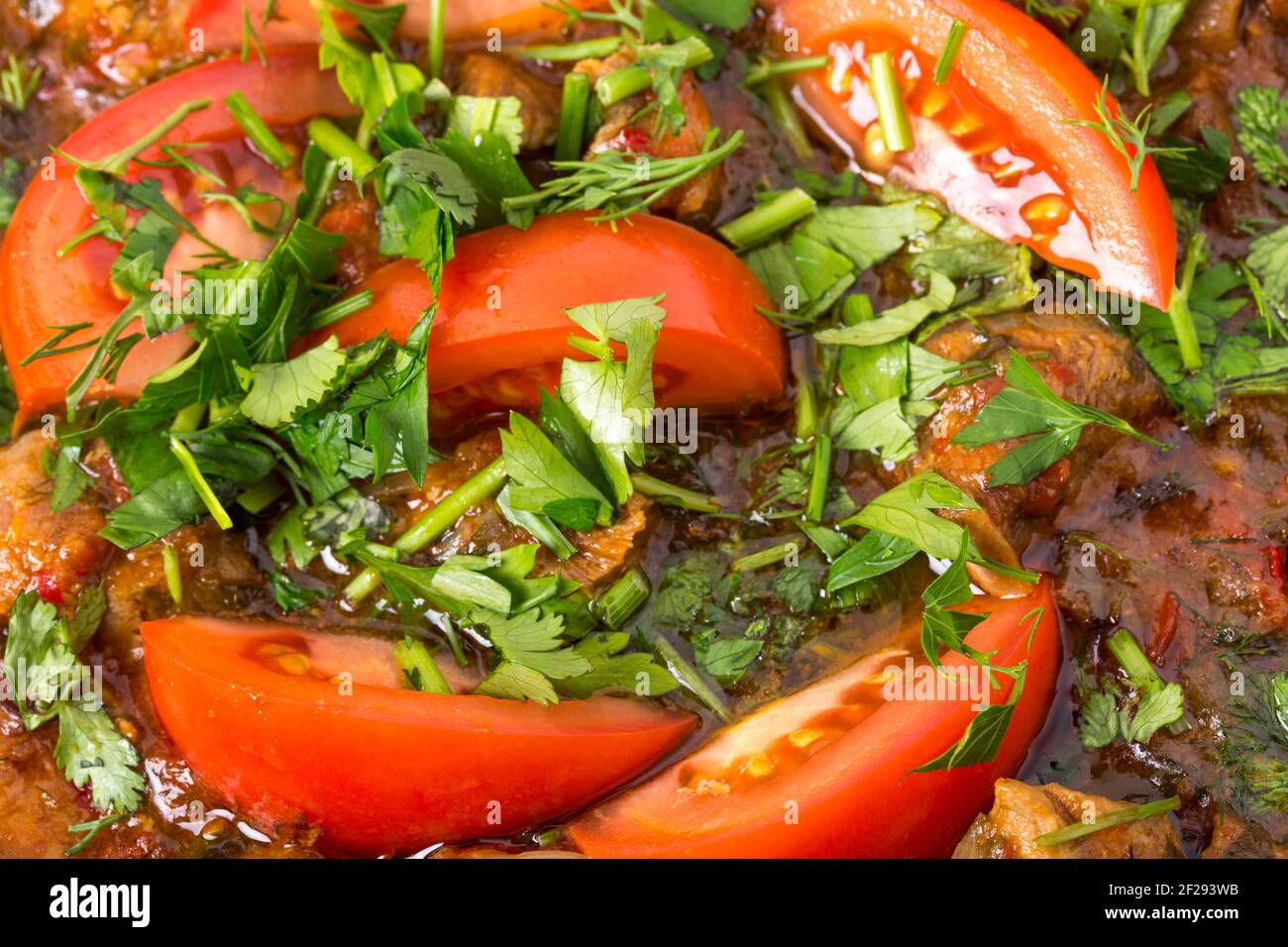Delicious stewed pork fillet with fresh tomatoes and minced parsley. Macro. Photo can be used as a whole background. Stock Photo