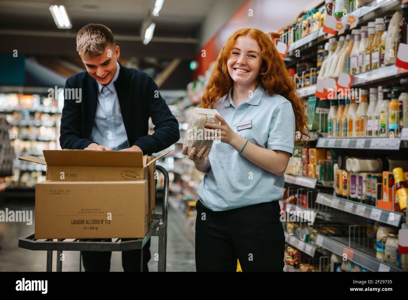 Young worker restocking the shelves with a colleague in the supermarket