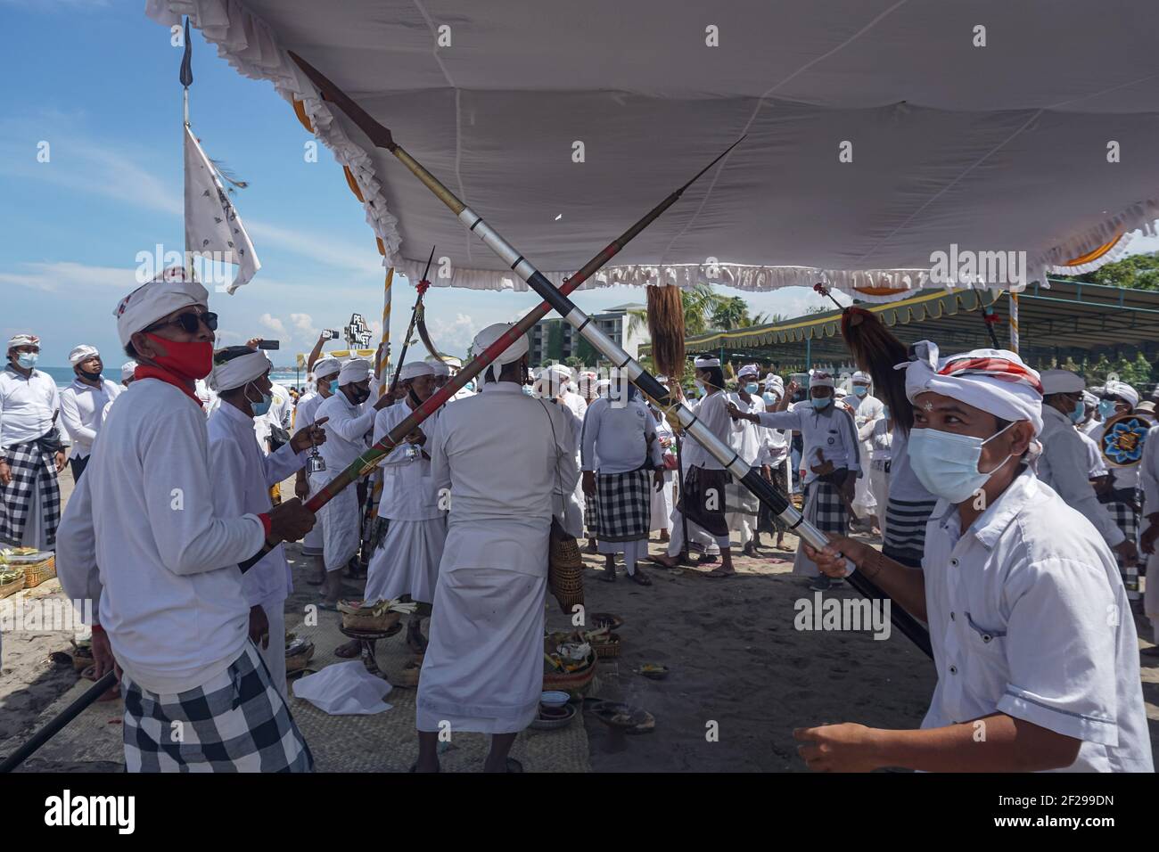 Badung, Bali, Indonesia. 10th Mar, 2021. Devotees performs an act of war during the event. Balinese Hindu to celebrate Melasti, a soul-cleansing ceremony at Petitenget Beach before Nyepi, the Day of Silence, holiday. Nyepi will be held on March 14, 2021, which marks New Year in Balinese calendar. By the Covid-19 outbreak, Melasti this year only limited for few selected people. In the normal condition there are thousands of them. (Credit Image: © Dicky BisinglasiZUMA Wire) Stock Photo