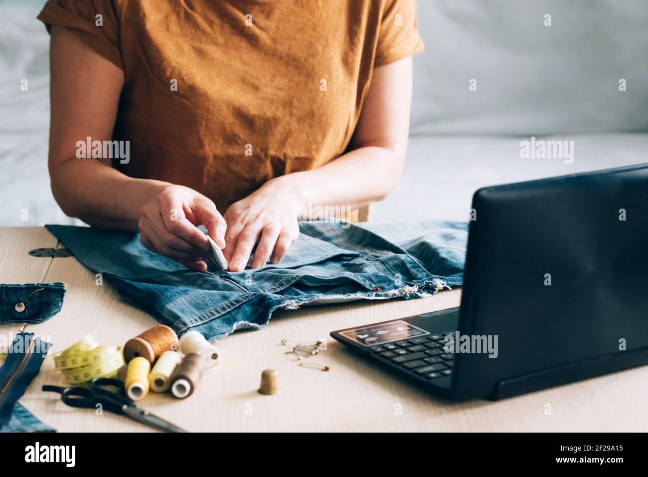 A woman is engaged in online training and looks at sewing lessons on a laptop. Concept of trendy online learning taking courses at home. Homemade need Stock Photo