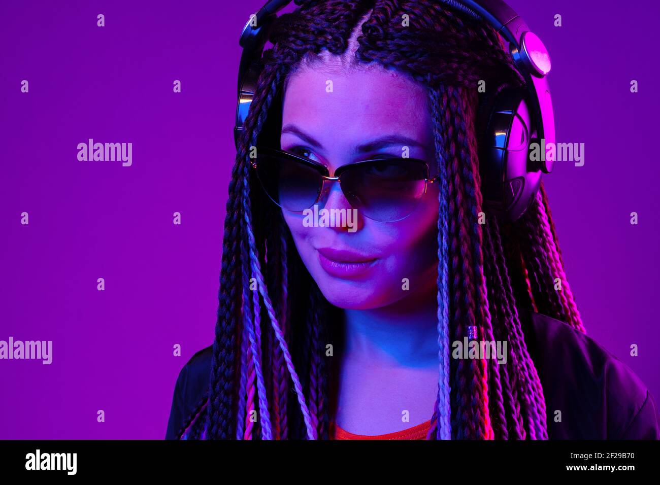 Beautiful woman with long hair in braids listening to music with ...