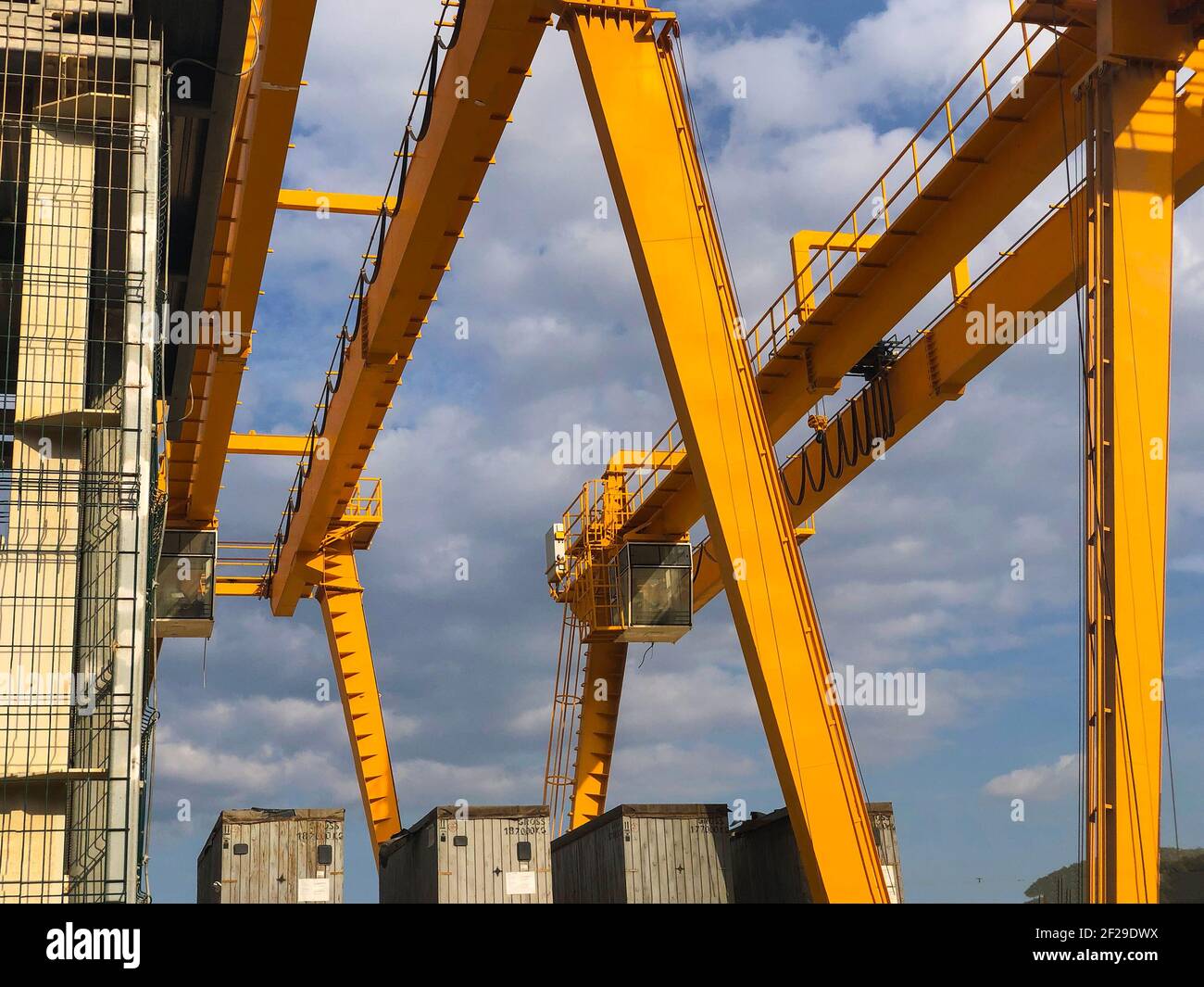 Gantry cranes opposite cloudy sky. Industrial lifting machinery. Hoist