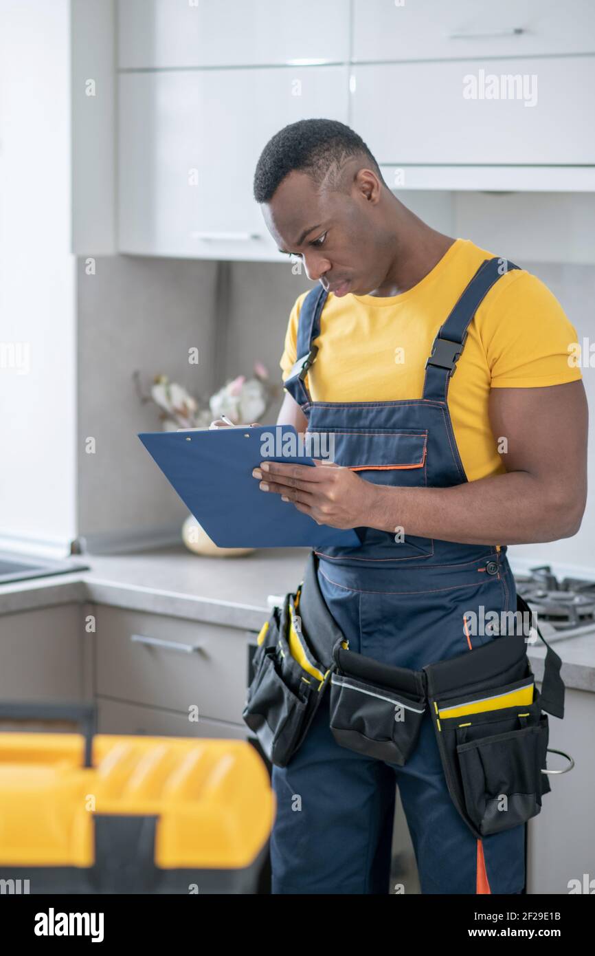 Service Man Images Dark-skinned service man standing in the kitchen and making notes Stock ...
