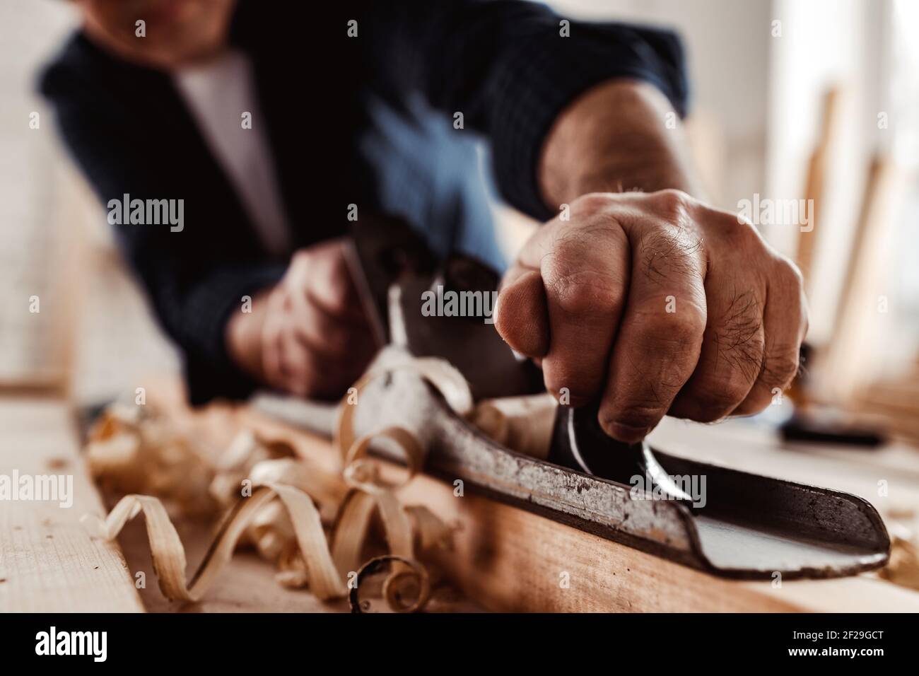 Carpenter's hands planing a plank of wood with a hand plane Stock Photo