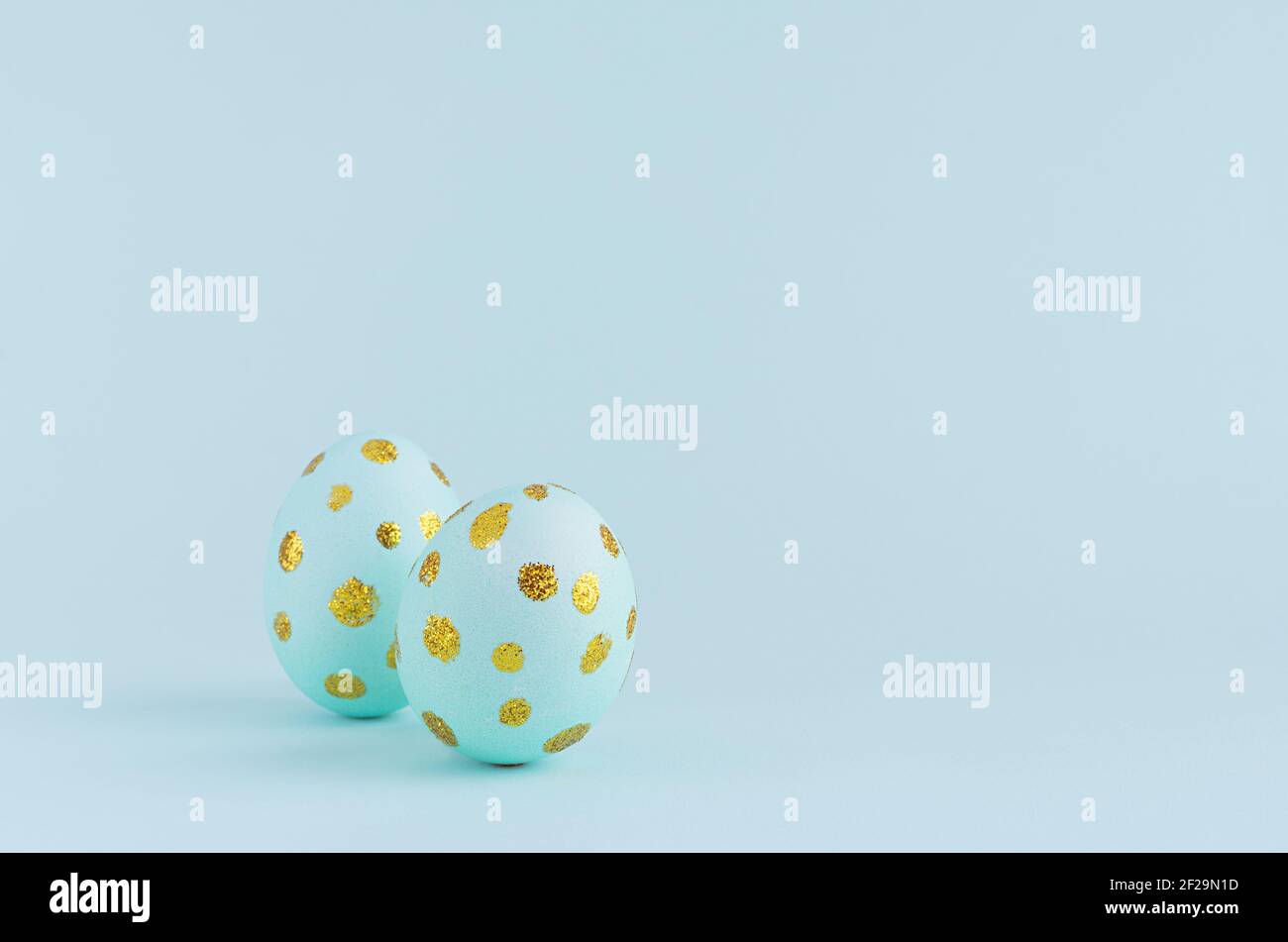 Elegant easter eggs with gold dots on blue background, copy space. Stock Photo