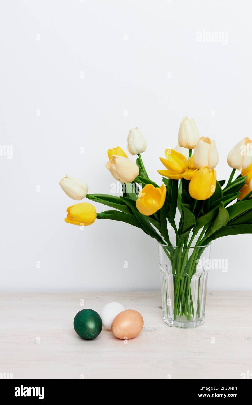 Yellow tulips in a vase and multi-colored eggs on the Easter table ...