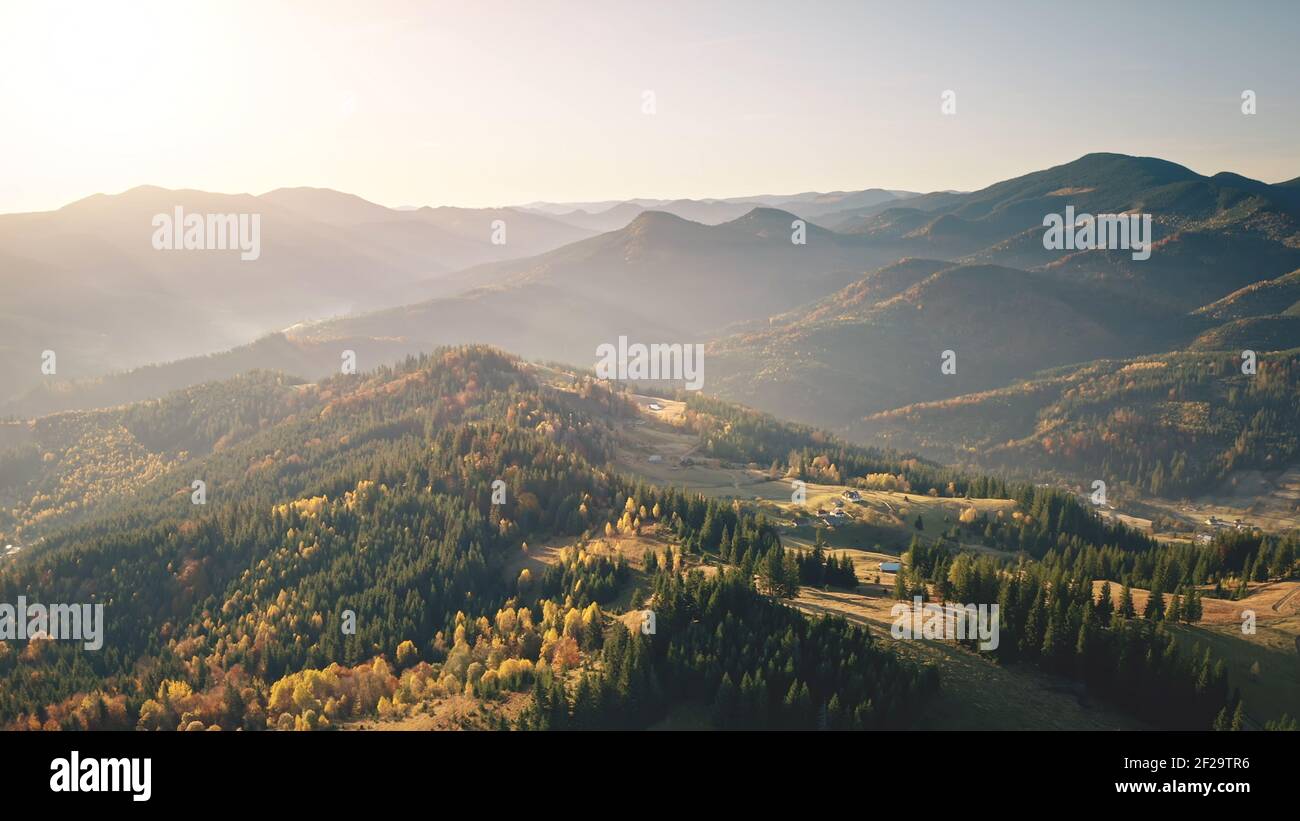 Fog sunrise at mountain village aerial. Autumn nobody nature landscape. Green spruce, leaf forest. Cottages, buildings on mount hills. Countryside vacation at Tatra, Poland, Europe. Cinematic sunlight Stock Photo