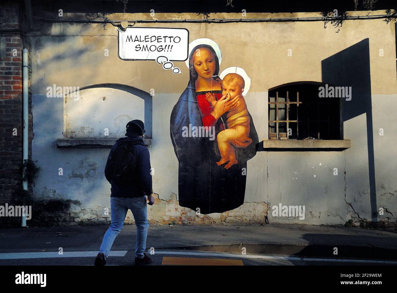 Padua, Italy. A mural of Mary, mother of Jesus against smog. Virgin Mary plugs with her fingers the nose of baby Jesus. Stock Photo