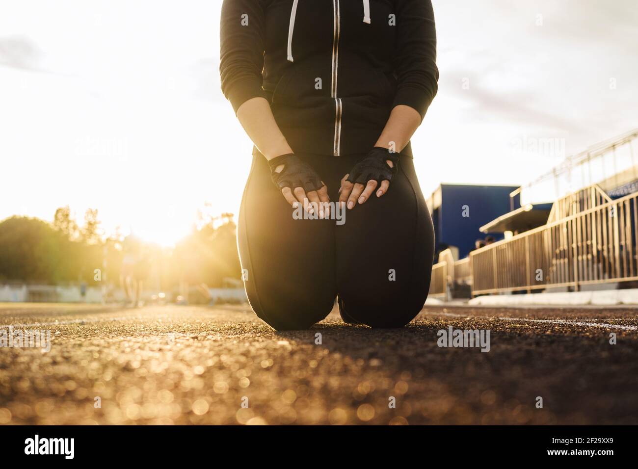 Fitness woman lifestyle in black tracksuit outdoor, white sunny sky background. Sunset light, selective focus. Stock Photo