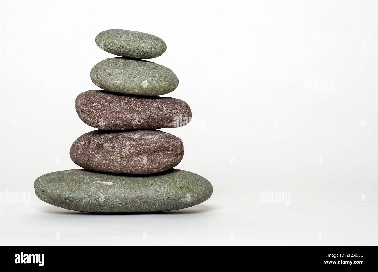 Stones balanced on one another against a white background Stock Photo
