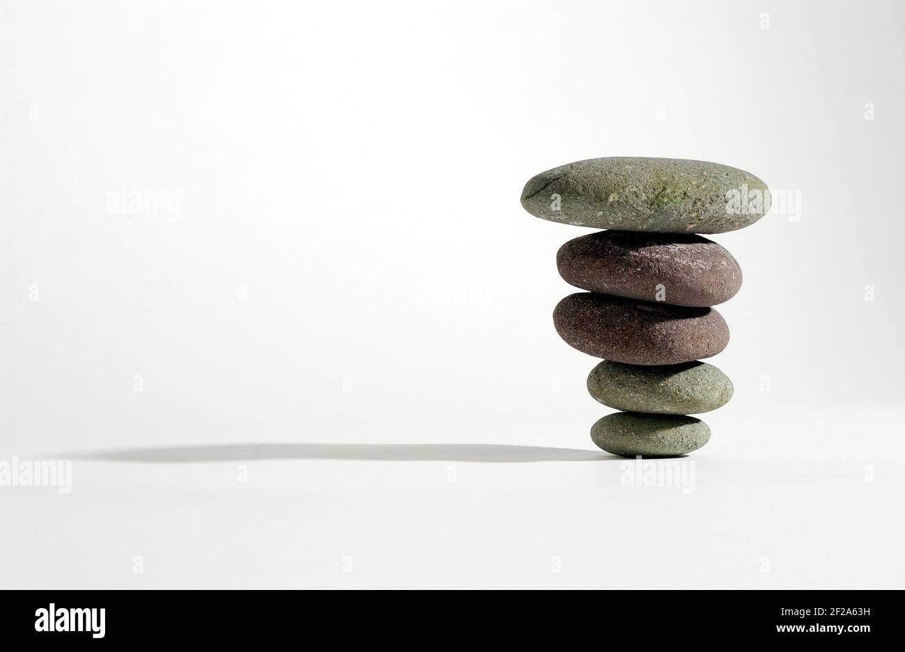 Stones balanced on one another against a white background Stock Photo