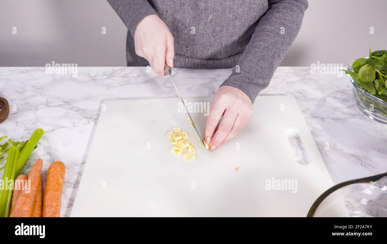 Curring vegetables on a white cutting board to cook vegetarian white bean soup. Stock Photo