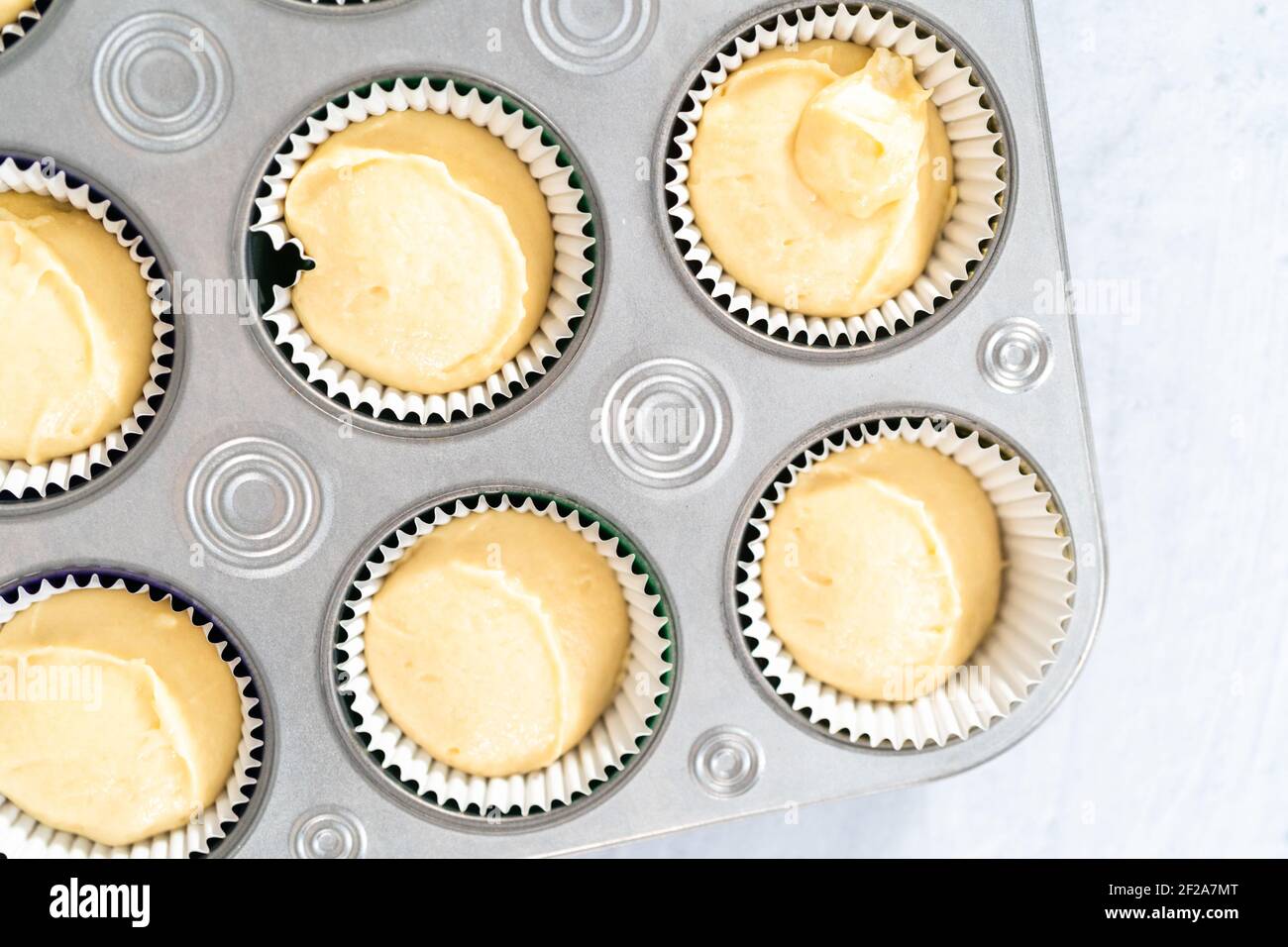 Vanilla cupcake batter in foil cupcake liners to bake Mardi Gras