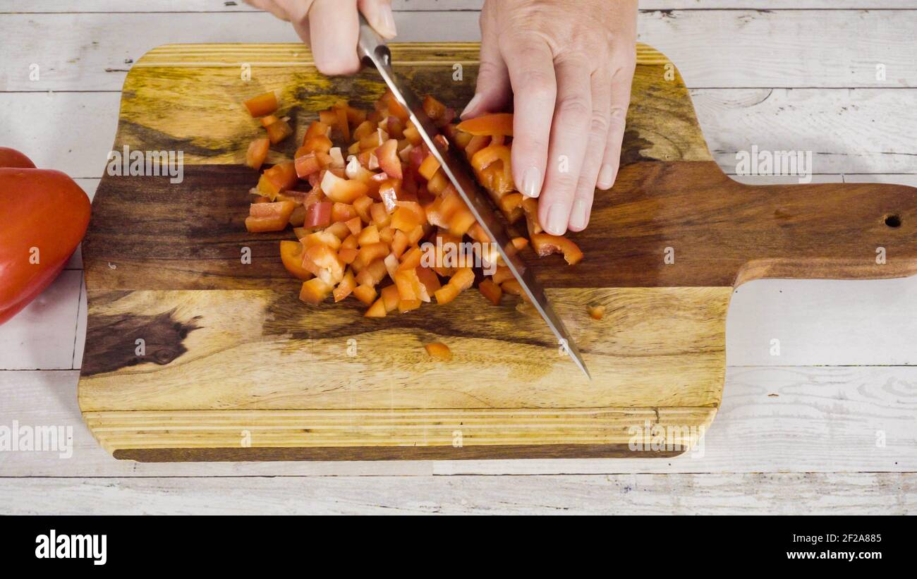 Mincing organic red bell peppers on a wood cutting board Stock Photo ...