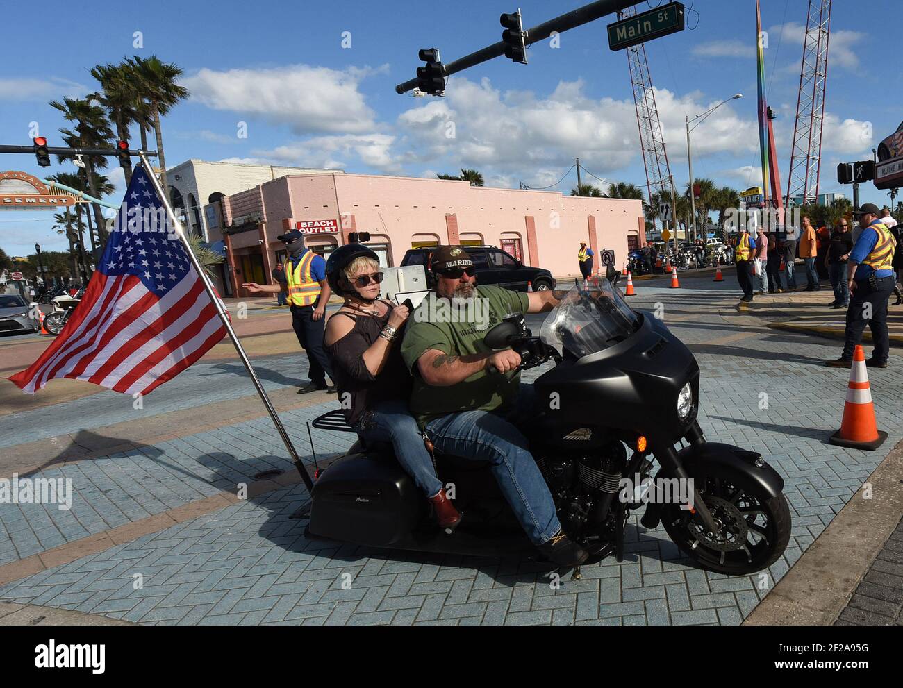 Daytona Beach, United States. 10th Mar, 2021. A motorcyclist carries an American flag as he rides down Main Street during the 80th year of Daytona Beach's annual Bike Week event. Few people were seen wearing face masks or practicing social distancing and some worry the gathering could become a superspreader event as the coronavirus pandemic continues. Credit: SOPA Images Limited/Alamy Live News Stock Photo