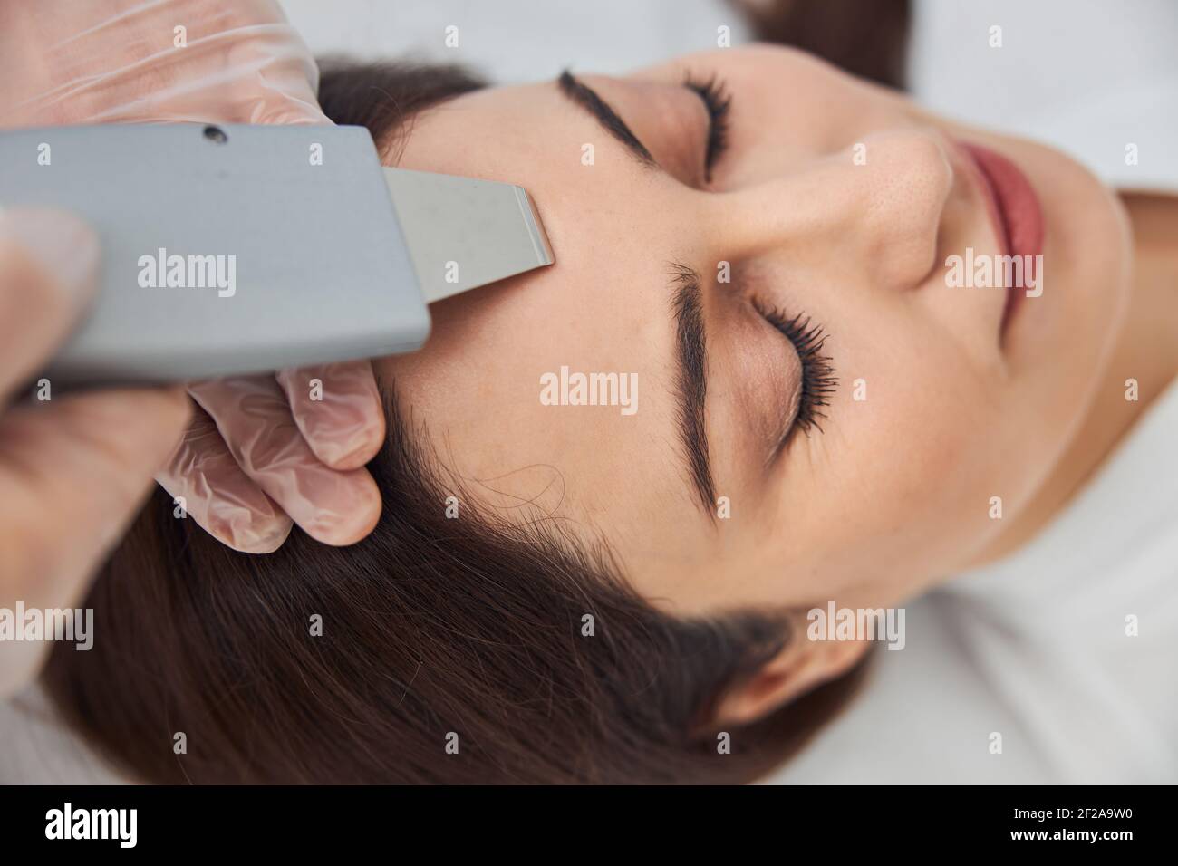 Charming woman receiving facial treatment at wellness center Stock Photo