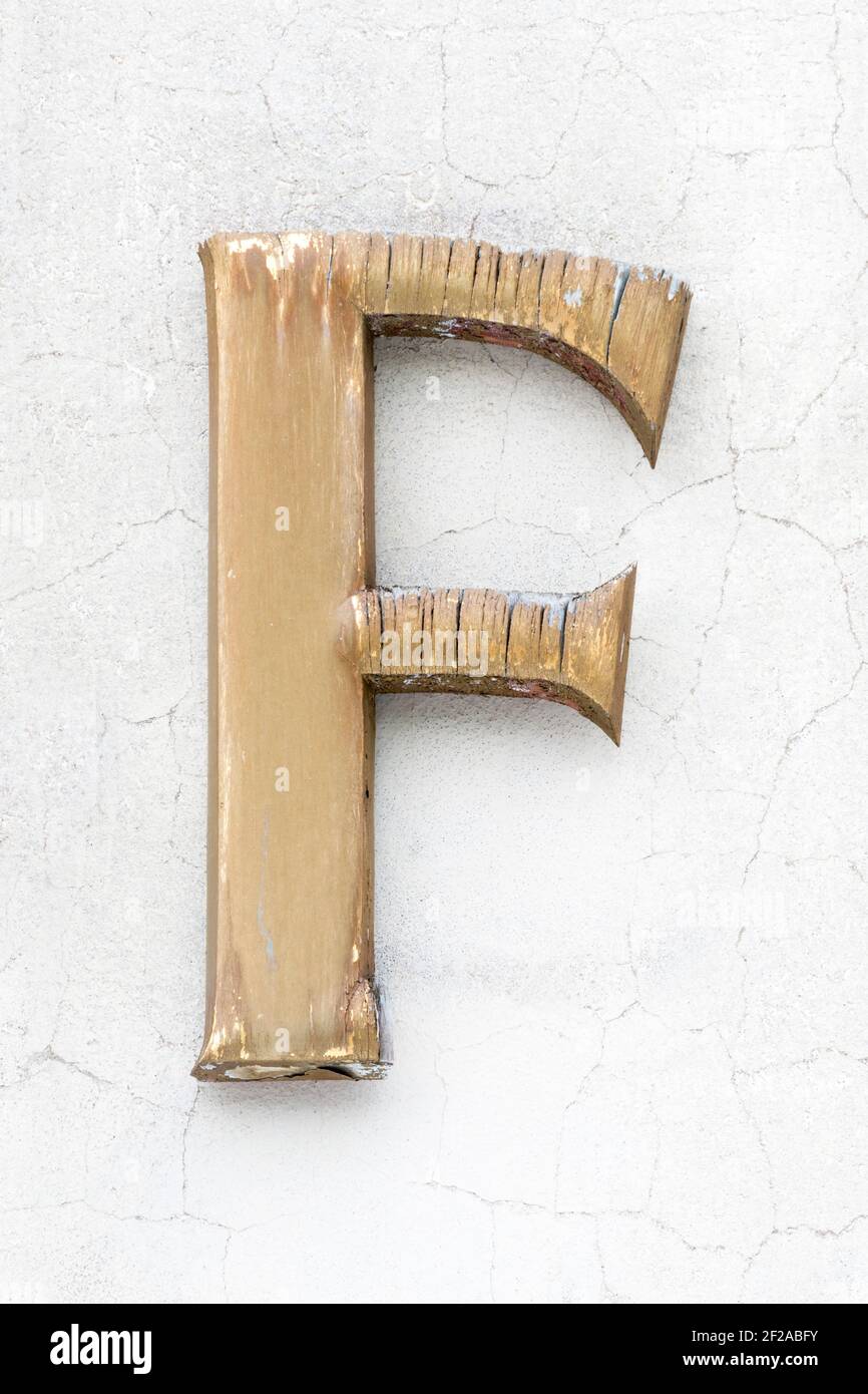 Weathered wooden letter F in golden colour Stock Photo