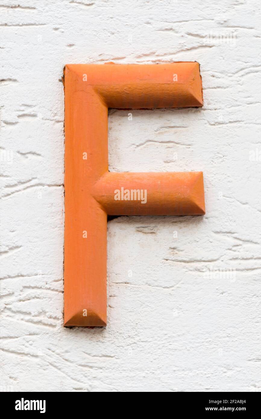 Orange letter F on a white house wall Stock Photo