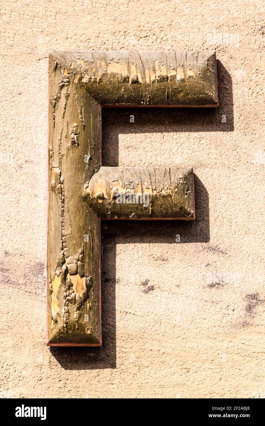 Weathered gilt capital letter F Stock Photo