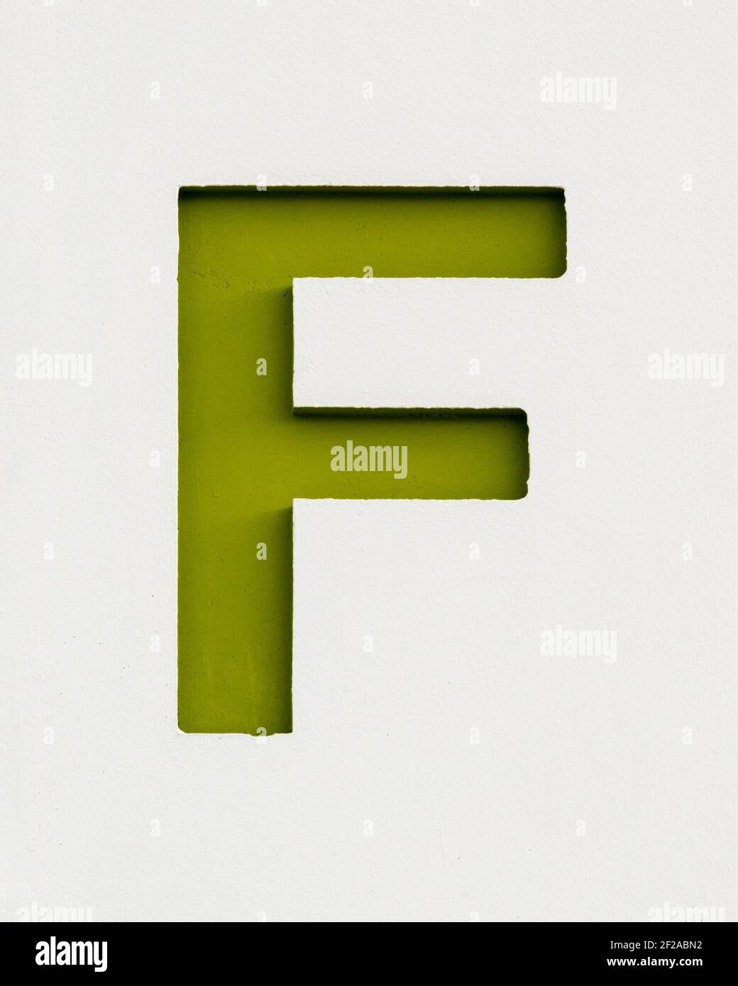 Olive green letter F inverse relief on a concrete wall Stock Photo