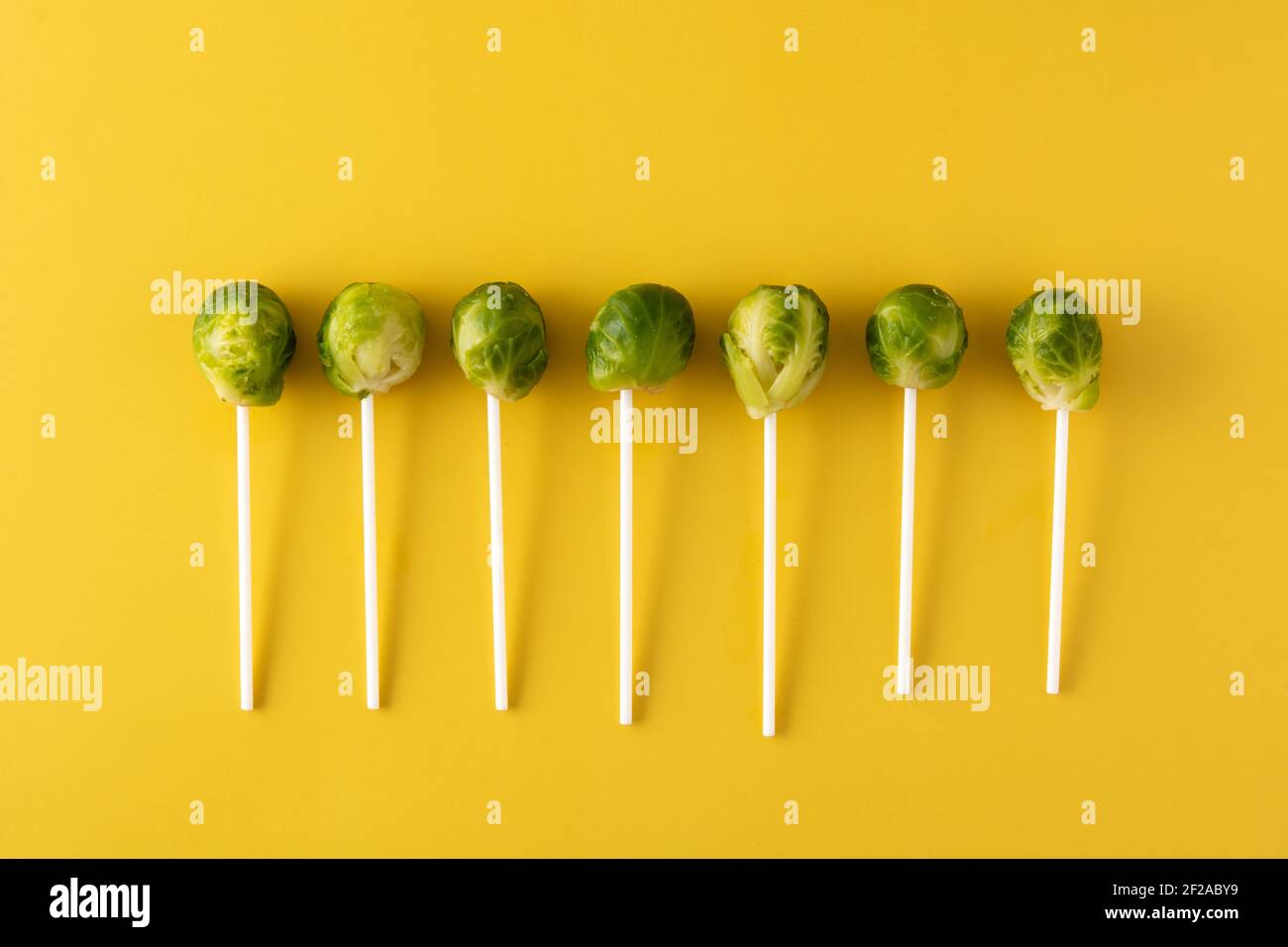 Set of brussel sprouts with lollipop sticks on yellow background Stock