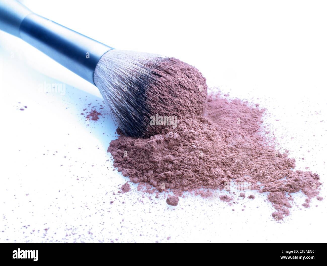 Shallow depth of field on brush and cosmetic loose powder on a stained white background. Slightly cool toned Stock Photo