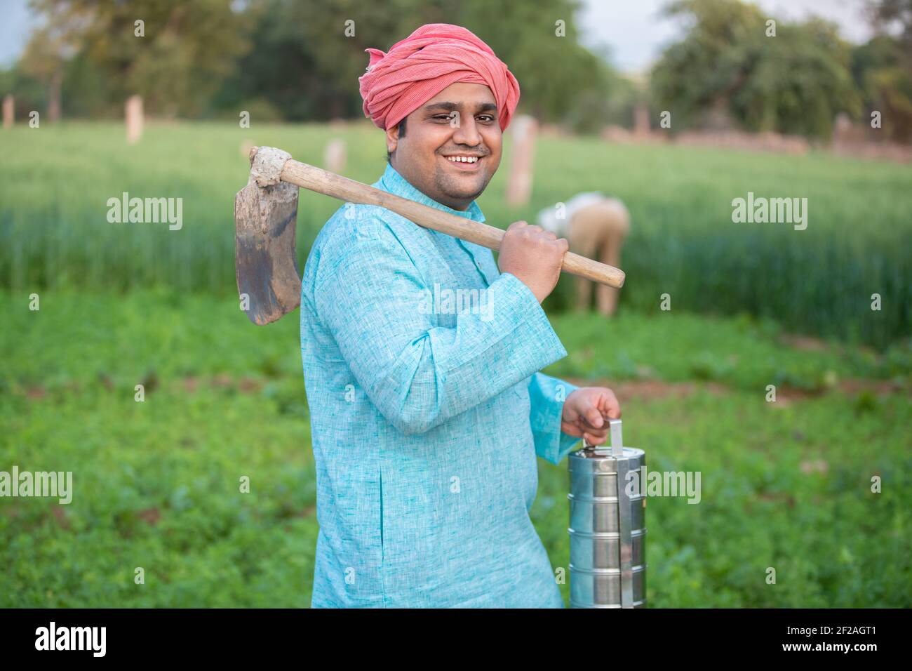 Portrait of happy indian male farmer holding Pretail Garden Spade / Shovel or agricultural tool and tiffing box. Stock Photo