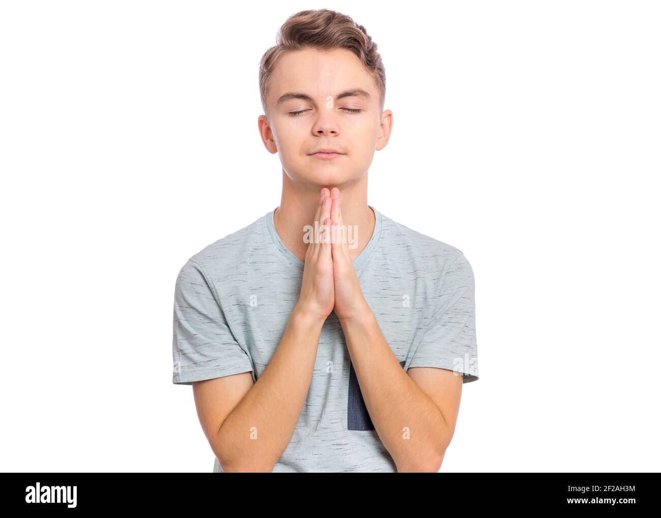 Handsome teen boy with hands folded in prayer hoping for better, isolated on white background Stock Photo