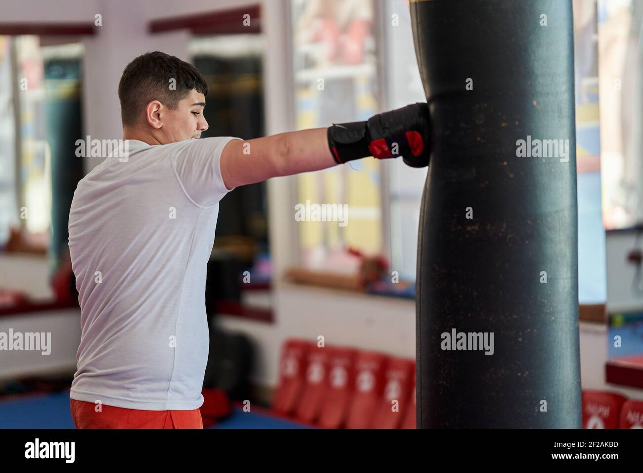 Overweight kickboxing fighter hitting the heavy bag in the gym Stock