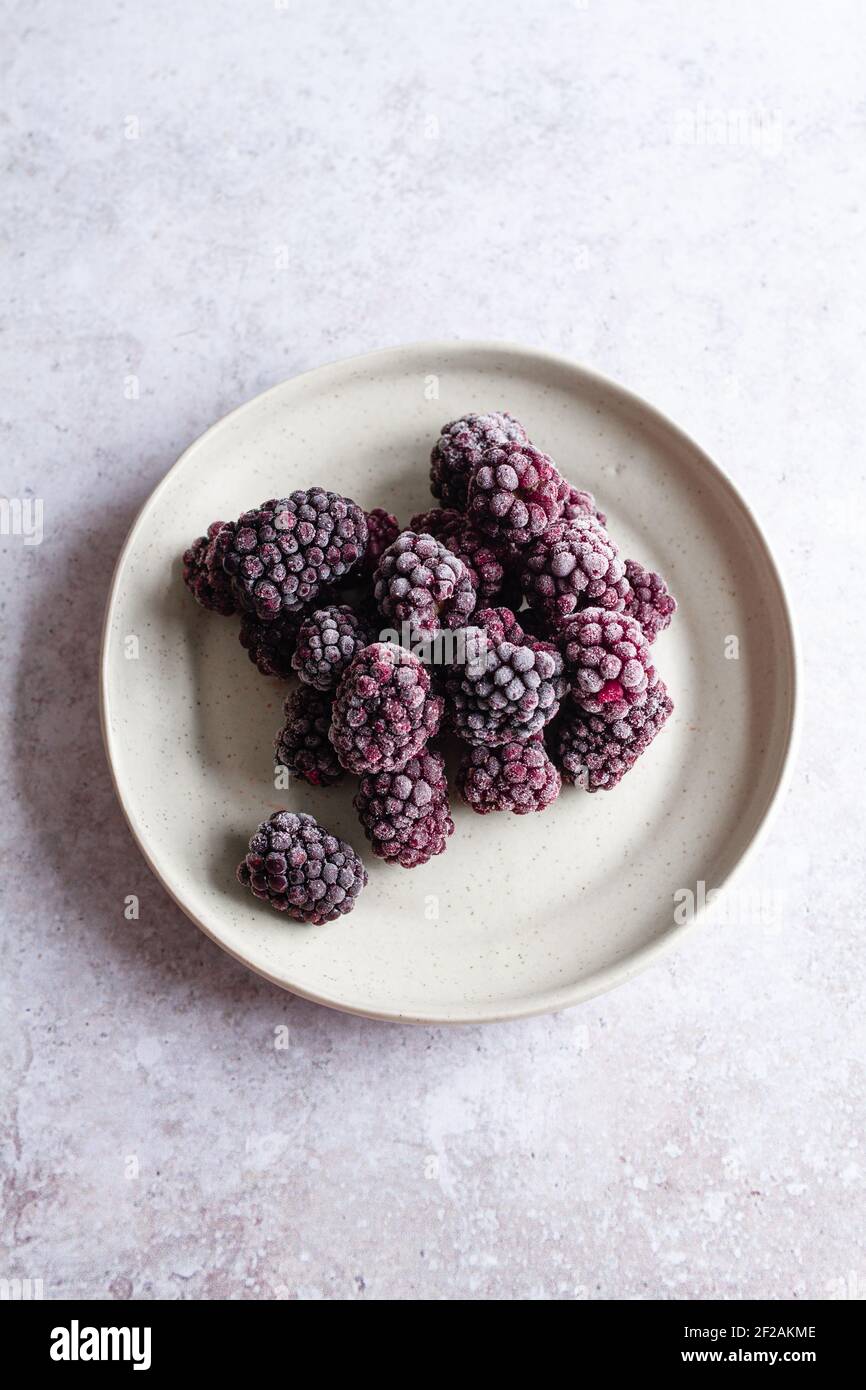 Small plate with frozen blackberries viewed from above. Stock Photo