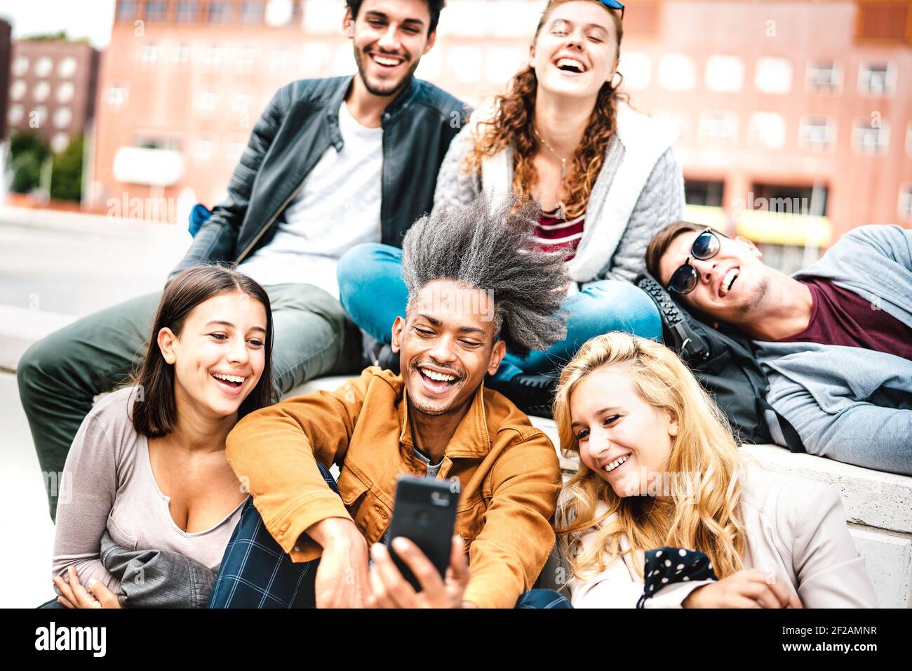 Happy milenial people having fun sharing photo on mobile phone after lockdown reopening - Joyful concept about guys and girls spending time together Stock Photo