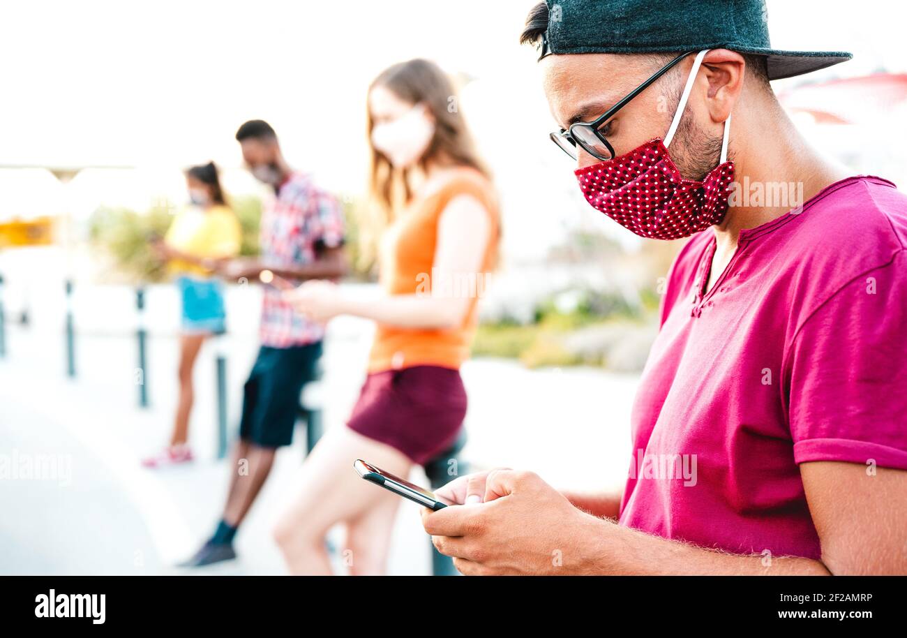 Millenial friends wearing disposable face mask using tracking app with mobile phones - Bored young people on smartphones outdoors Stock Photo