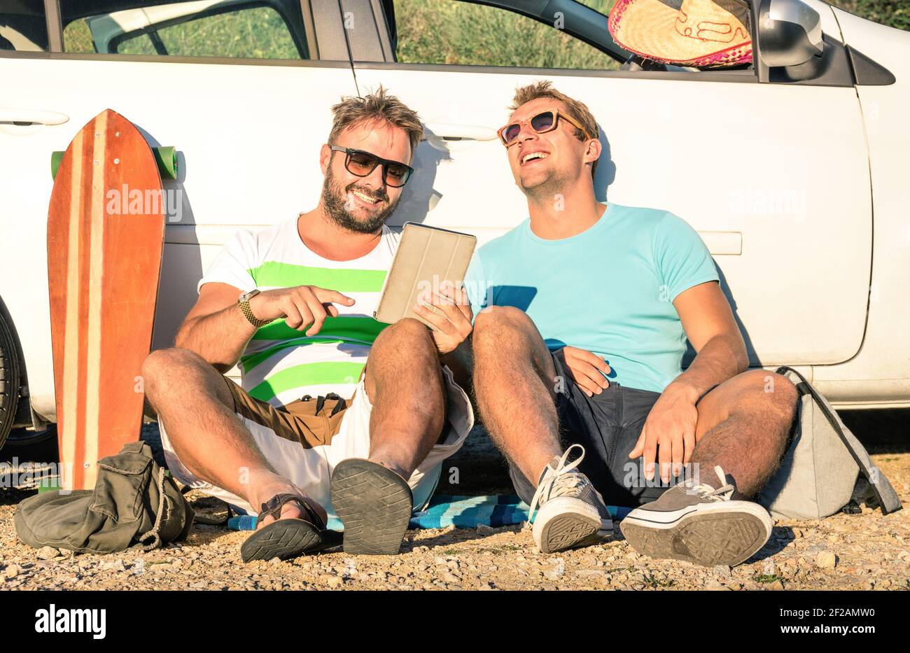 Young hipster best friends having fun with tablet during a car trip moment - Concept of modern technologies and new trends during alternative travel Stock Photo