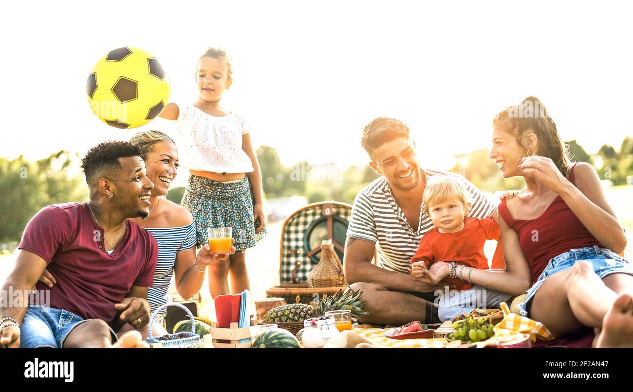 Happy multiracial families having fun together with kids at pic nic barbecue party - Multicultural joy and love concept with mixed race people Stock Photo