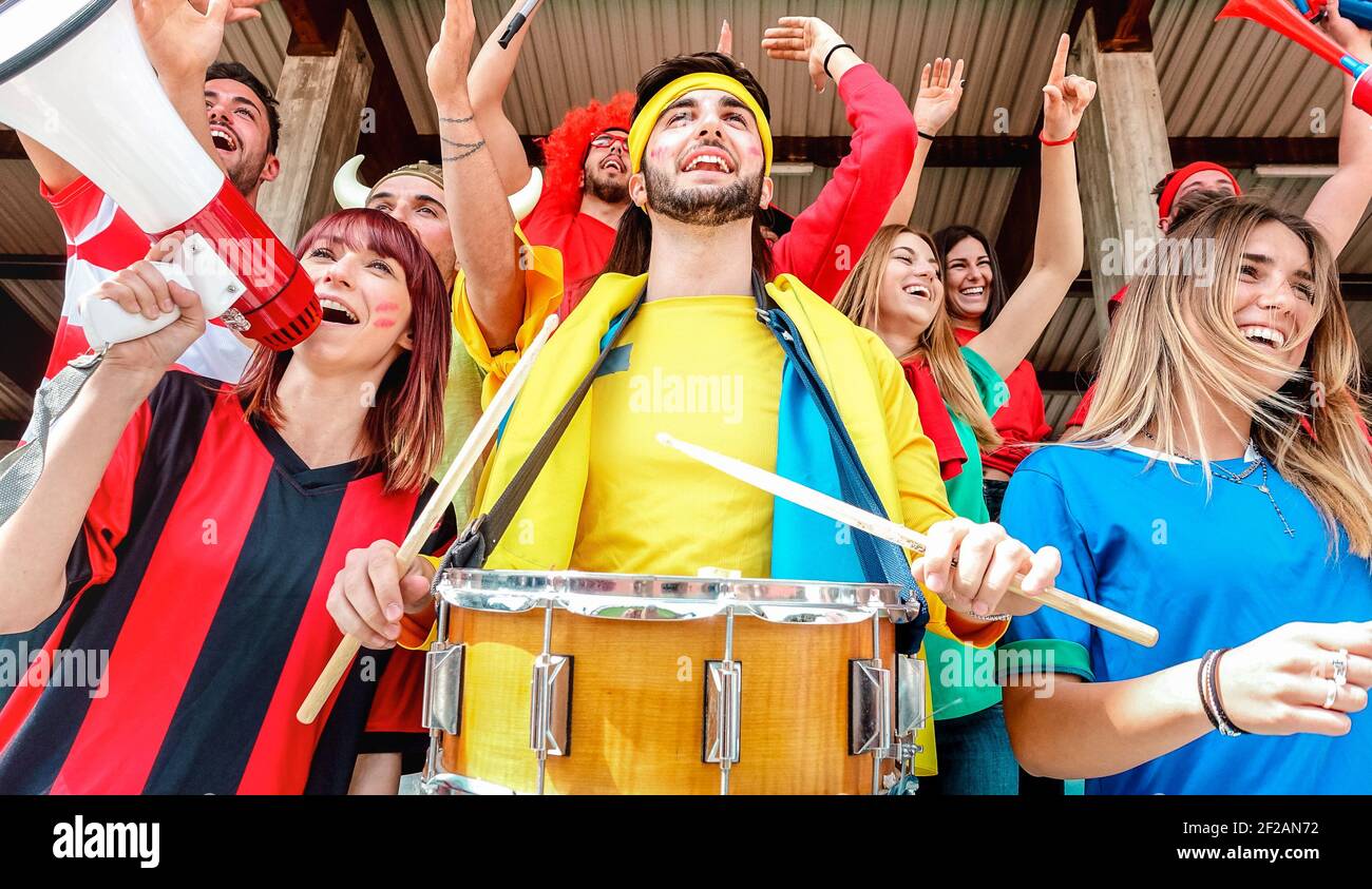 Soccer fan supporters cheering and watching football cup match at intenational stadium bleachers - Sport concept with young people group Stock Photo