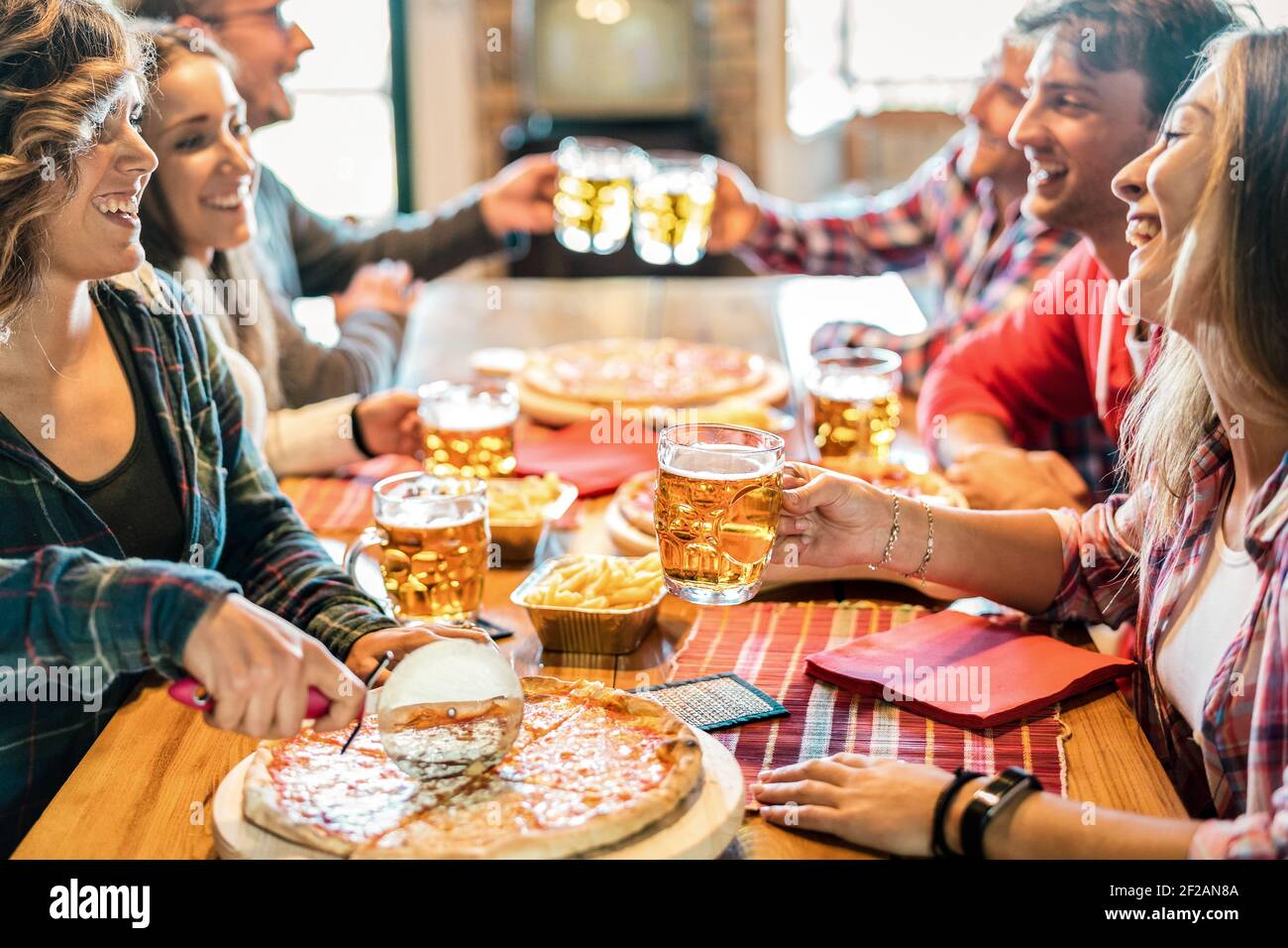 laughing friends eating pizza and having fun. They are enjoying eating and  drinking together Stock Photo